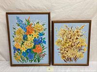 Shows two framed floral oil paintings side by side against a neutral backdrop