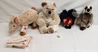 All four plush animals in a row on a white surface with tags visible. Bearing bear, beige gopher, black crow, and gray pig.