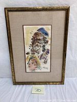 Full view of framed watercolor painting depicting two faces, beige matte, gold frame, artist signature visible.