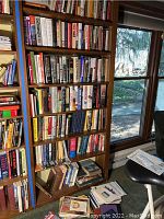 Full shelving unit with numerous books of various titles mostly related to WWII and German history, visible in shelves, with natural light from window.