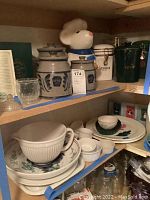 Overview of upper shelf showing Heinz 57 pottery containers, Gevalia coffee containers, ceramic mouse cookie jar, ramekins, mixing bowl and plates stacked.