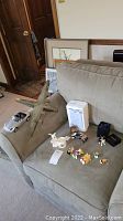 Photo showing a model airplane, a silver/chrome model car, several small Disney figurines, and a certificate of authenticity on a couch.