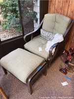 Overall view of chair and ottoman set with green cushions on enclosed porch