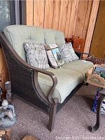 Front view of green cushioned La-Z-Boy outdoor loveseat with three throw pillows on seat