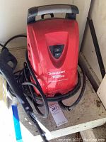 Front view of red Husky pressure washer showing on/off switch and 1500 PSI label, hoses wrapped around base