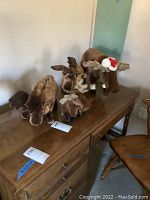 Four Steiff moose plush toys arranged on a wooden surface, showing size and texture differences