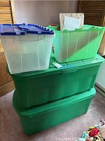 Four plastic storage tubs stacked and grouped in room corner.