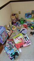 Photo shows a corner with various children’s toys, board games, costume pieces, and a pink and purple tutu skirt laid out scattered on floor.