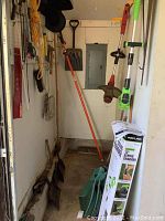 Corner with multiple garden tools, electric trimmers and storage items
