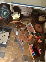 Overview photo showing wooden trays, bowls, terra cotta bakeware, pepper grinder, candle sticks, and decorative sign arranged on floor.
