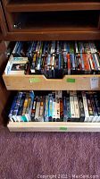 Drawers of wooden cabinet filled with DVDs and VHS tapes