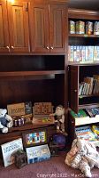 Shelf showing vintage board games, Chess boards, plush toys including a rag doll and a teddy bear, and small wooden game boxes.