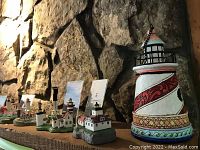 Overall view of multiple lighthouse figurines arranged on a surface against stone wall background