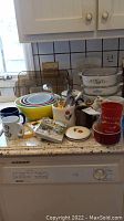 Full lot including Pyrex nested bowls, CorningWare casseroles, baking dishes, mugs, and kitchen utensils on countertop