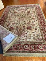 Full view of Shaw nylon area rug approximately 5x8 with cream base and floral patterns, slightly lifted corner showing backing and thickness