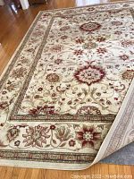 Top view of the ivory rug with rust and beige floral patterns showing corner and part of border detail.
