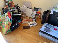 Photo showing several office supplies including binders, Crayola crayons, colored pencils, writing pad, map, and tote bags arranged on wood floor.