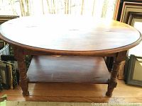Photo showing the whole wooden side table with turned legs and lower shelf, placed on wooden floor with natural light.