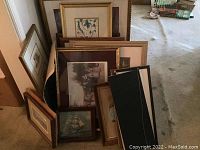 Photo showing multiple framed vintage art and pictures stacked together, view of various frame styles and sizes.