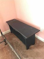 Full view of the black wooden bench showing overall shape and condition.