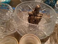 Close-up of cut glass covered butter dish marked Rosenthal showing starburst pattern, clear glass bowl with hobnail texture, and small bronze figurine.