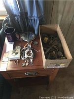 Overview photo showing assortment of costume jewelry, mug, hand mirror, paperweight, and box of buckles and keys on a wooden desk.