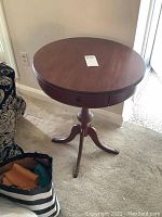 Full view of round drum table showing tabletop, single drawer, and part of pedestal support.