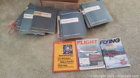 Lot overview showing several blue Martin Marietta instructional booklets and three aviation magazines Airline Business, Flight International, and Flying laid out on carpet