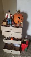 Overview of lot showing four-drawer cardboard organizer with ornaments inside, Santa figurine on top and plastic pumpkin beside it