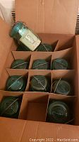 Box containing 11 blue-green Ball Ideal Mason jars with metal wire bale lids.