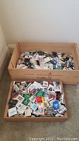 Two wooden boxes filled with assorted matchbooks from various establishments.