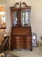 Full front view of the vintage solid wood secretary desk with glass doors, slant front desk surface, and four drawers beneath.