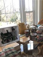 Wide view of the teapots, pitcher, and glassware on a glass-top table by a window