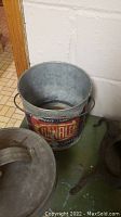 Metal bucket labeled Gambler, showing item's vintage condition and heavy use signs