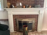 Wide shot of fireplace mantle and immediately surrounding area showing various decorative items including elephant figurines, fishbowl, vintage flower pots, resin planter, and umbrella stand.