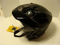 Side view of glossy black Bell MAG9 helmet with attached face shield and chin strap, new with tag.