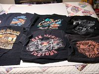 Top view of six black Harley-Davidson T-shirts folded, showing a variety of graphic prints.