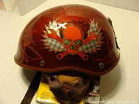 Side view of the Bell Speed Shop XL motorcycle helmet showing the orange metallic paint and skull and crossed wrench graphic on the side with red pinstripe accents.