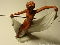 Front angled view showing the nude female dancer bisque figurine holding a white cloth wide to the sides, with detailed hair and oval base.