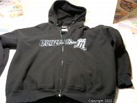 Black zippered hoodie laid flat showing front Harley Davidson logo and hood.