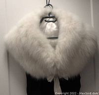 Front view of white rabbit fur stole on hanger showing full collar and satin ties, exhibiting its size and fluffiness.
