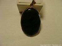Front view of the oval dark green stone set in the gold bezel.