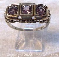 Front view of the sterling silver ring showing three amethyst stones in individual square bezels with Art Nouveau inspired design on the ring shoulders.