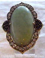 Close-up of the ring front showing large oval jade and surrounding cubic zirconia stones with spinel accents.