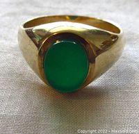 Front view of ring showing oval green cabochon bezel set in yellow gold.