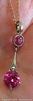 Close-up front view of the pendant showing large prong set pink sapphire and smaller bezel set pink sapphire above, with white gold setting and small diamond accent.