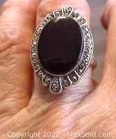 Front view showing large black onyx stone surrounded by marcasite accents set in sterling silver ring on finger.