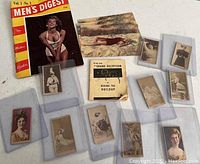 Overview photo showing all items together: Mens Digest magazine, Marilyn Monroe postcards, and 10 antique burlesque advertising cards in protective sleeves.