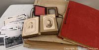 Various photographs showing the worn 1800s photo album, tin type portraits, daguerreotype photograph, loose black and white photos, and scrapbooks with handwritten notes and cards.