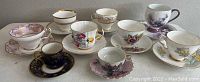 Photo showing a group of assorted vintage European porcelain cups and saucers with floral and decorative designs
